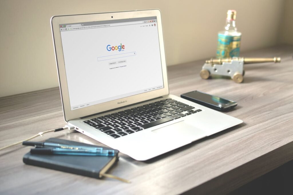 pexels-photo-67112 A neat workspace featuring a laptop displaying Google search, a smartphone, and a notebook on a wooden desk.