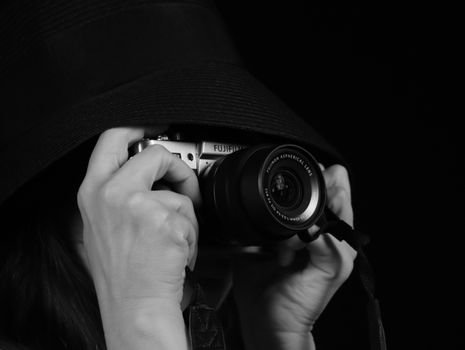 pexels photo 35269947 35269947 Black and white portrait of a person using a camera partially hidden by a hat.